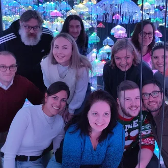 Gruppenfoto des Denkströme-Teams in einer immersiven Lichtinstallation mit leuchtenden Kunst-Objekten – Teamgeist, Kreativität und Freude sichtbar vereint