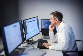 Webentwicklung Denkströme IT-Spezialist arbeitet konzentriert an mehreren Monitoren – Softwareentwicklung und Programmierung im modernen Büro