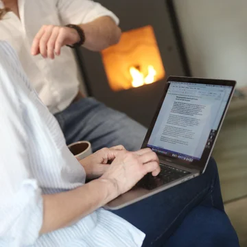 Frau arbeitet mit Laptop im gemütlichen Raum mit Kamin