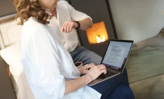 Pressearbeit Frau arbeitet mit Laptop im gemütlichen Raum mit Kamin