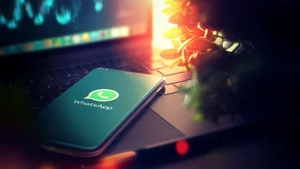 WhatsApp Marketing Smartphone mit WhatsApp-Logo auf Laptop-Tastatur im Sonnenlicht – Kommunikation, Mobile Messaging, digitale Vernetzung