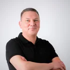 Porträt von Thomas Schmid im schwarzen Polohemd mit verschränkten Armen