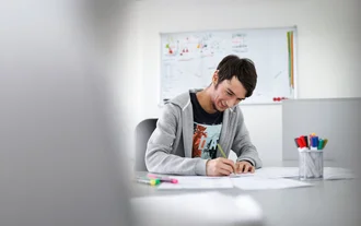 Markenpositionierung Junger Denkströme Grafiker arbeitet konzentriert an Markenentwürfen im kreativen Büro der Denkströme Gruppe