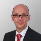 Porträt von Stefan Krotschek im Anzug mit weißem Hemd und roter Krawatte