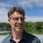 Porträt von Markus Brzuske im dunklen Hemd, Außenaufnahme mit blauem Himmel, schaut freundlich