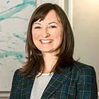 Dr. Katharina Richter im karierten Blazer – sympathisches Business-Porträt vor modernem Kunsthintergrund für Kundenstimmen und Referenzen