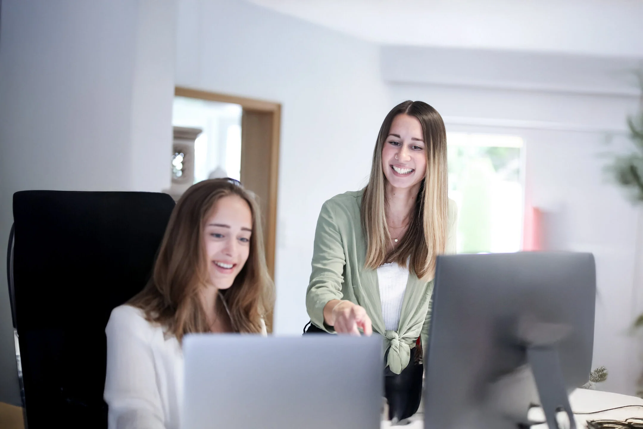 Zwei junge Denkströme Mitarbeiterinnen arbeiten gemeinsam am Computer im modernen Büro – kollegiale Zusammenarbeit und digitale Projektarbeit