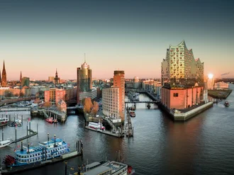 Panoramaansicht des Hamburger Hafens mit Elbphilharmonie bei Sonnenuntergang, Boote im Vordergrund