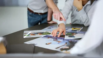 Kampagnen Design Denkströme Team analysiert Werbemotive mit medizinischem Fokus für Recruiting und Employer Branding am Tisch – kreative Zusammenarbeit im Gesundheitsmarketing