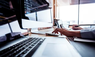 Website Relaunch Nahaufnahme einer Person an Tastatur und Monitor in moderner Büroumgebung – Programmierung oder IT-Arbeit mit Fokus auf Code und Technik