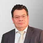 Etzel Walle im seriösen Business-Outfit – professionelles Porträt eines erfahrenen Unternehmers vor neutralem Hintergrund für Kundenreferenz